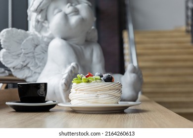 Pavlova dessert and a cup of coffee on the table. White angel