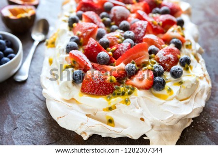 Pavlova meringue cake with berries and passionfruit.  Side view on slate.