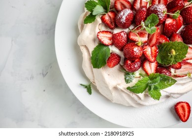 Pavlova Meringue Cake Decorated With Fresh Strawberries And Whipped Cream. Food, Culinary, Baking And Cooking Concept.