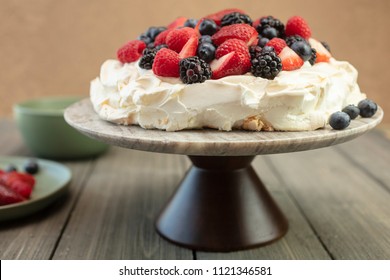 Pavlova meringue cake dessert made with strawberries, blackberries, raspberries and blueberries,  planted on a granite platform