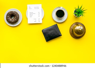 Pay The Bill, Pay At Restaurant. Check Near Wallet, Service Bell, Coffee On Yellow Background Top View Space For Text