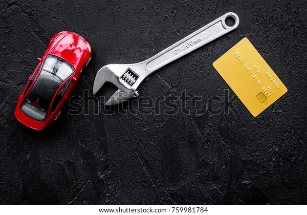 Pay for car repair. Wrench\
near car toys and bank card on black background top view\
copyspace