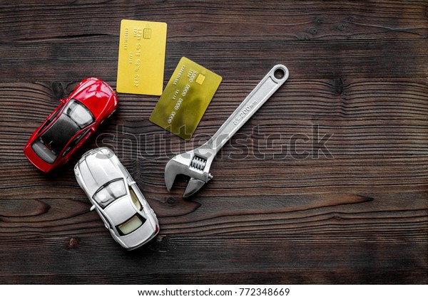 Pay for car repair. Wrench\
near car toys and bank card on dark wooden background top view\
copyspace