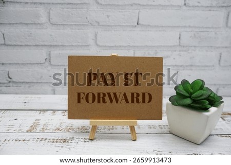 Pay It Forward text message with easel stand on wooden background