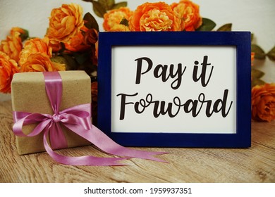 Pay It Forward Typography Text With Gift Box And Flower On Wooden Background