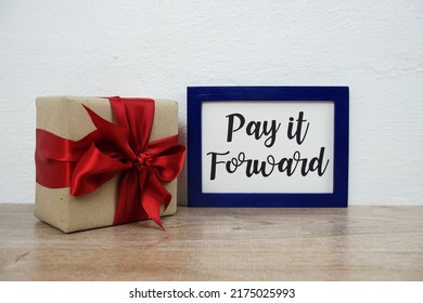 Pay It Forward Typography Text And Gift Box On Wooden Table And White Wall Background