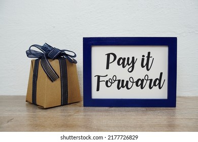 Pay It Forward Typography Text And Gift Box On Wooden Table And White Wall Background