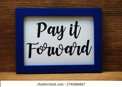 Pay It Forward Written With Blue Photo Frame On Wooden Background