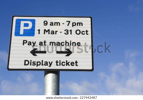 Pay at machine car\
park sign when parking between 9am and 7pm, March to October\
against a partly cloudy\
sky.