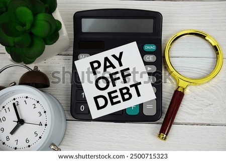Pay Off Debt text message with calculate, alarm clock and magnifying glass on wooden background