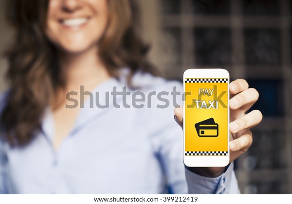 Pay Taxi\
message and credit card icon on a mobile phone screen. Woman\
holding smart phone with taxi booking\
app.