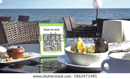 Pay touch-free with a QR code. QR code scanning app. Touchless digital payment option for businesses. A man sits in an open cafe on the beach