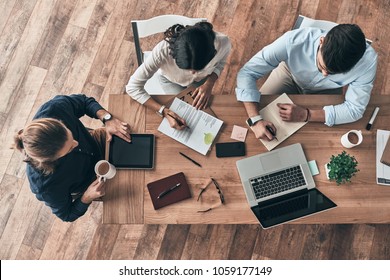 Paying Attention To Every Detail. Top View Of Young Modern Colleagues In Smart Casual Wear Working Together While Spending Time In The Office