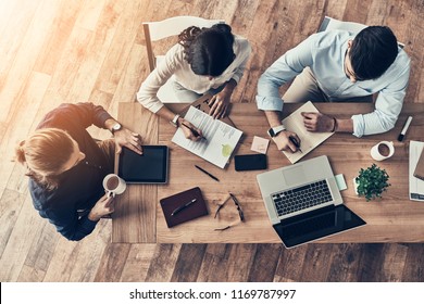 Paying Attention To Every Detail. Top View Of Young Modern Colleagues In Smart Casual Wear Working Together While Spending Time In The Office