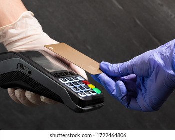 Paying With A Gold Credit Card Contactless Nfc At POS With Medical Gloves On Black Background. Nfc Pay. Covid Pay. Pos Technology. Cashless Payment During Quarantine.