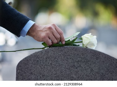 Paying his respects. Cropped shot of a man placing a white rose on a grave. - Shutterstock ID 2129308964