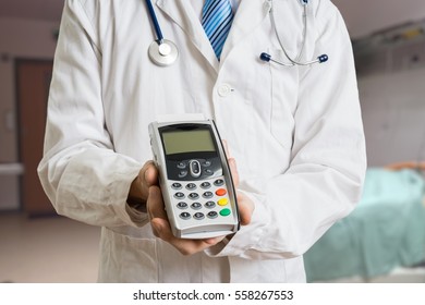 Paying For Private Healthcare. Doctor Holds Payment Terminal In Hands.