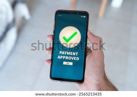 A Payment approved notification on smart phone held by hand.