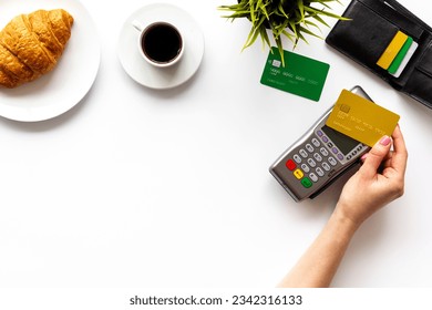 Pago con tarjeta de crédito por café y cruasán. Pos terminal de pago con cartera.