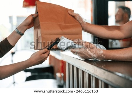 Payment by using terminal, order is ready. Man is serving delicious street food.