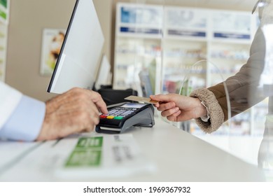 Payment of drug bills. A close-up of the payment terminal at the counter and sweeping the card for the purchase of medicines in the pharmacy. Female and male hands in focus - Powered by Shutterstock