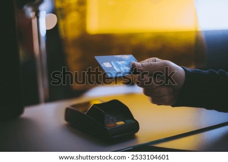 Payment for purchases in the store using a terminal and a bank card. Close-up. The hand applies a plastic card to the payment terminal