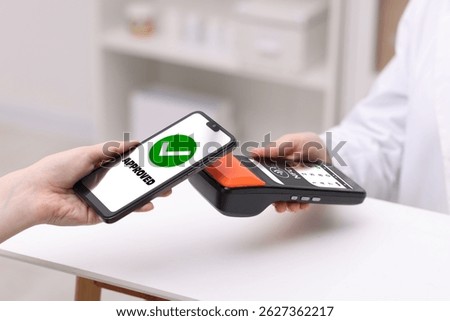 Payment terminal with NFC system. Client using mobile phone to pay for service in hospital, closeup