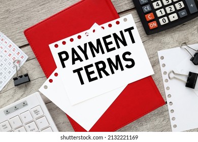 PAYMENT TERMS. red notebook on the table. text on a notepad page. miscellaneous office supplies