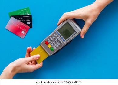 Payments In Shops. Hand Insert Bank Card In Terminal On Blue Background Top-down