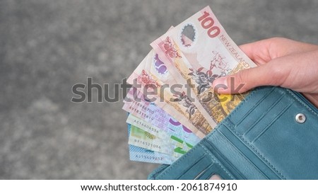 Payout Concept - Person Holding New Zealand Bank Notes hundreds, fifties, twenties and tens in a Wallet, selective focus with copy space