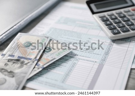 Payroll. Tax return forms, calculator and dollar banknotes on table, selective focus
