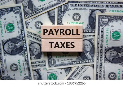 Payroll Taxes Symbol. Concept Words 'Payroll Taxes' On Wooden Blocks On A Beautiful Background From Dollar Bills. Business And Payroll Taxes Concept.