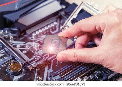 PC CPU Intel in the hands of a technician against the background of the motherboard Gigabyte. Computer parts. Desktop computer assembly and upgrade concept