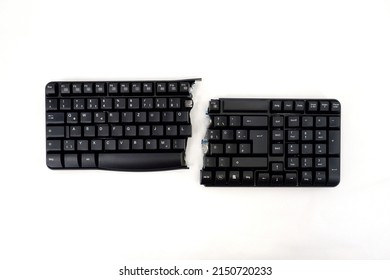 PC keyboard is cut into two parts. A black computer keyboard broken in half with an English Qwerty layout , isolated on a white background . View from above.