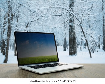 pc on wooden table, winter forest background