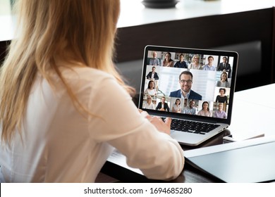 Pc screen view over woman shoulder at group video call. Visual communication between engaged diverse people distantly using webcam and laptop internet connection app. International remote chat concept - Shutterstock ID 1694685280