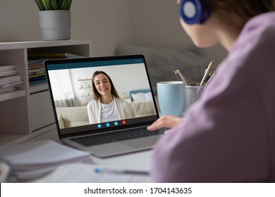 Pc screen view over woman shoulder, two girls best friends chatting using virtual modern video conference application communicating from home enjoy distant talk. Teacher teach learner remotely concept - Shutterstock ID 1704143635