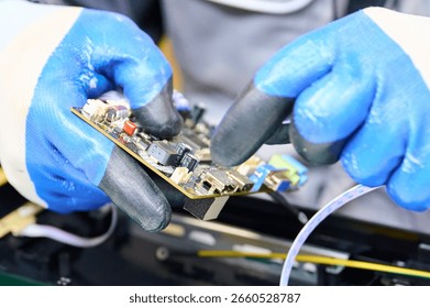 PCB assembly process in electronics manufacturing with technician using gloves and tools