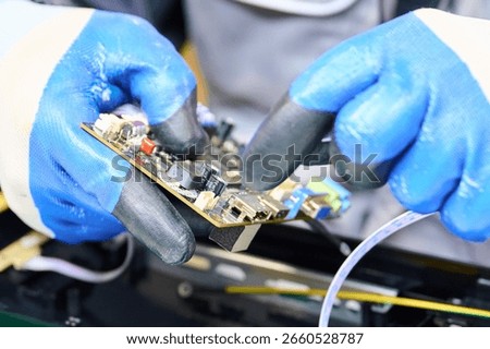 PCB assembly process in electronics manufacturing with technician using gloves and tools