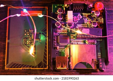 PCB with microchip, microprocessor, wires, neon lights, qubit, capacitor on the wooden table. Technologies, IT and computing theme
