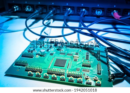 PCB testing. Printed circuit board is connected to tester. Several wires are connected to PCB. Concept - checking the microcircuit after production. Testing microcircuits in production.
