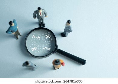 PDCA (Plan, Do, Check, Act) cycle,continuous improvement concept. A magnifying glass focuses on puzzle pieces of the PDCA method, with miniature business people figures analyzing the workflow.