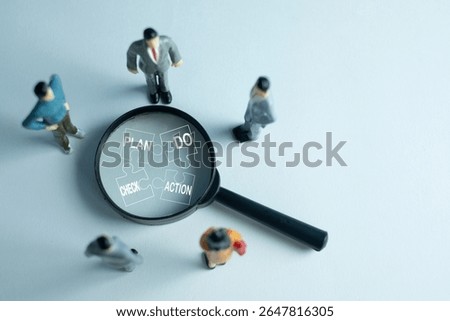 PDCA (Plan, Do, Check, Act) cycle,continuous improvement concept. A magnifying glass focuses on puzzle pieces of the PDCA method, with miniature business people figures analyzing the workflow.