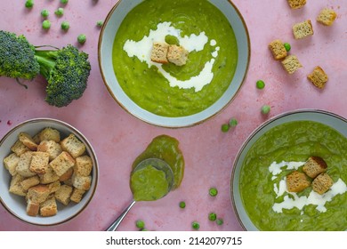 Pea And Ham Soup On Pink Background With A Spoon, Croutons And Cream Drizzle 