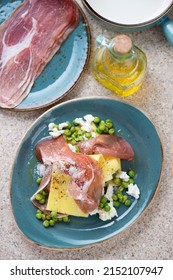 Pea, Ricotta And Prosciutto Open Lasagna Served On A Turquoise Plate, Above View On A Beige Marble Background, Vertical Shot