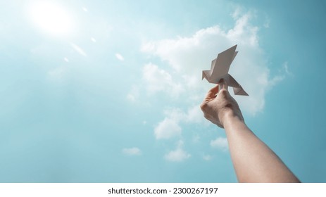 Peace, Hope concepts. World International Peace Day. Sustainable and Responsible Business, Hand Raise up a Paper Origami White Dove into the Sky - Powered by Shutterstock