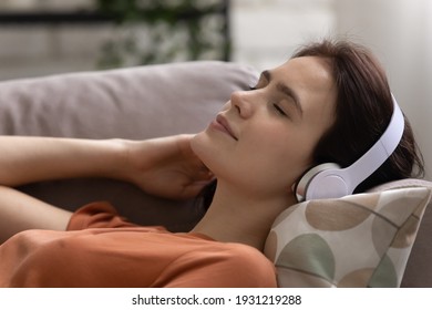 Peace Of Mind. Peaceful Female Teenager Lie On Comfy Couch On Soft Pillow Wear Wireless Headphones Enjoy Good Meditative Music. Serene Young Woman In Headset Relax Listen To Audiobook With Closed Eyes