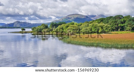 Peace and tranquillity on Lough Leane, Killarney, Ireland, with fluffy white clouds reflected in the calm lake waters.