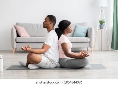 Peaceful african american couple sitting on fitness mat in lotus position back to back and meditating together, living room interior, copy space. Healthy lifestyle, yoga, pilates, exercising concept - Powered by Shutterstock