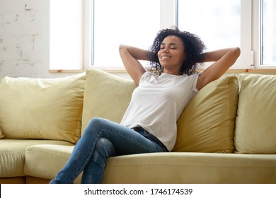 Peaceful African Young Woman Resting Leaned On Comfy Couch In Modern Living Room With Air-conditioner. Enjoy Fresh Air At Summer Day, Relaxing Alone Relish Lazy Day. No Stress Fatigue Relief Concept